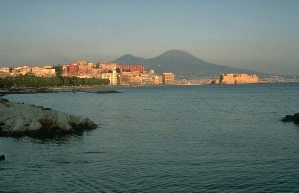 Mount Vesuvius behind city of Naples. The modern cone of Vesuvius is flanked on the left by Monte Somma, the rim of a caldera that formed about 17,000 years ago. Eight major explosive eruptions have occurred since, including the 79 CE eruption that destroyed Pompeii and other towns. A period of frequent, long-duration eruptions began in 1631 and the latest eruption of Vesuvius was in 1944. Photo by Dan Dzurisin, 1983 (U.S. Geological Survey).