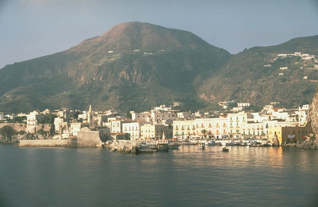 Lipari, the largest of Italy's Aeolian Islands, was constructed during four eruptive cycles beginning around 100,000 years ago. Monte Giardina lava dome on the S side of the island, seen here from the NE with Lipari city in the foreground, formed during about 23,000 to 17,000 years ago. Holocene eruptions formed the Pomiciazzo lava dome and the Rocche Rosse and Forgia Vecchia obsidian flows. Photo by Richard Waitt, 1985 (U.S. Geological Survey).
