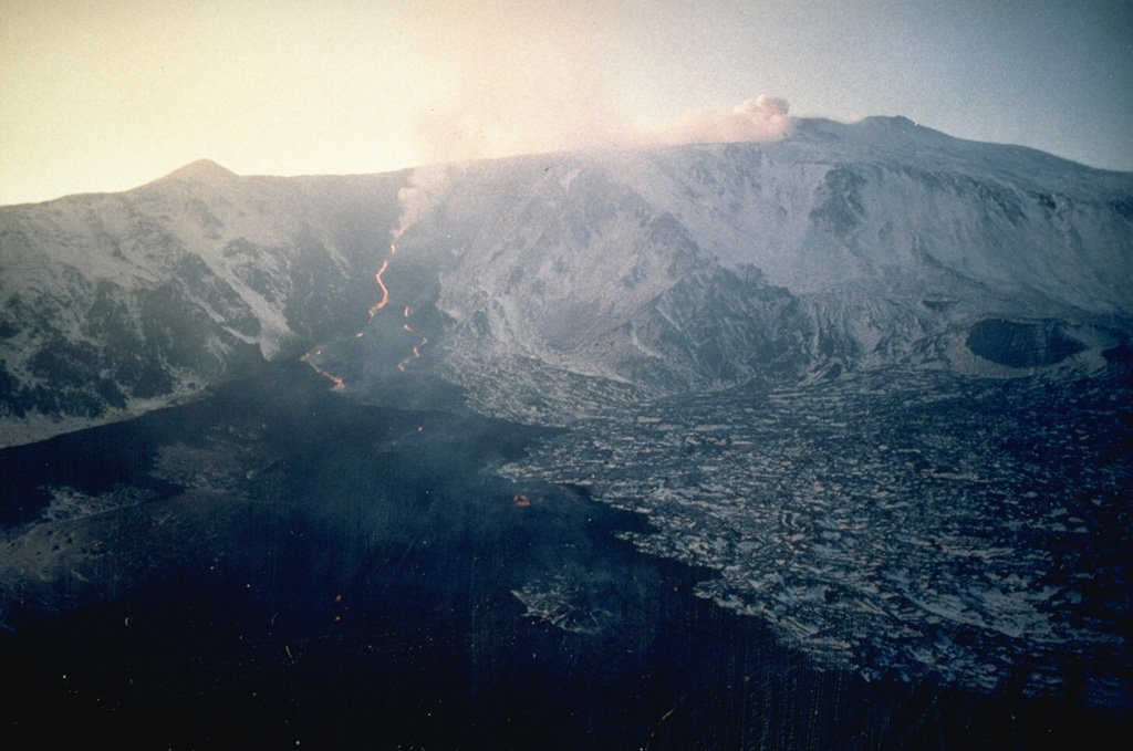 This 31 December 1991 view of Etna from the E shows lava flows descending the headwall of the Valle del Bove. This eruption began from the Southeast Crater and nearby fissures and lasted until 30 March 1993. The eruption was Etna's largest during the past 300 years, producing 0.3 km3 of lava that descended 7.5 km down the flank. Photo by Jean-Claude Tanguy, 1991 (University of Paris).