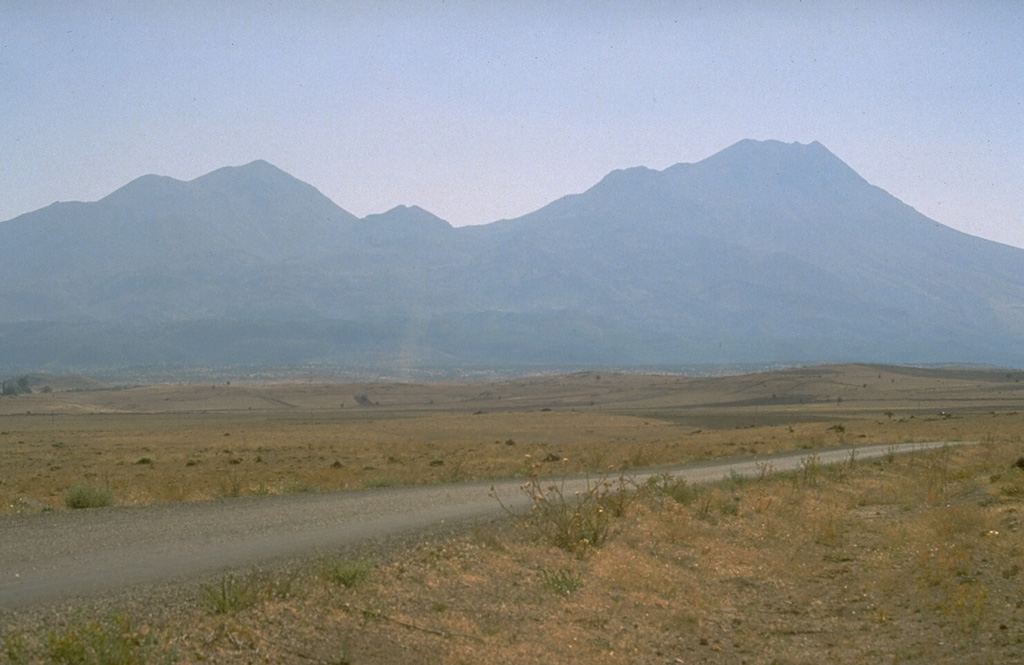 The double-peaked Hasan Dagi volcano in central Turkey has a complex history that includes three episodes of caldera collapse. Numerous cones, maars, and lava flows dot the flanks of the volcano. The hilly terrain in the foreground is a debris avalanche deposit produced by collapse of the volcano. Photo by Richard Waitt, 1994 (U.S. Geological Survey).