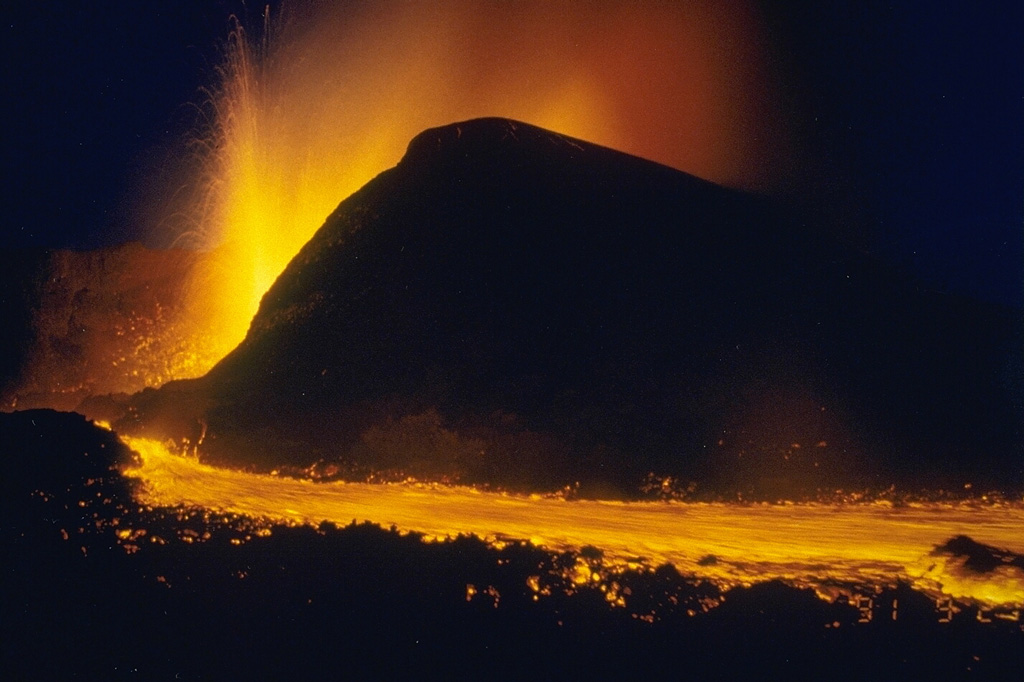 Lava fountains from the new cone of Mikombe on the lower NE flank of Nyamuragira volcano feed the lava flow in the foreground. This photo was taken from the SE on 29 September, nine days after the start of the eruption. During the first week the new cone grew to a height of 60-70 m. Lava flows had traveled 6-7 km NE by the time of this photo. The eruption continued until February 1993, by which time lava flows had traveled 19 km NE. Photo by Minoru Kasahara, 1991 (Hokkaido University).