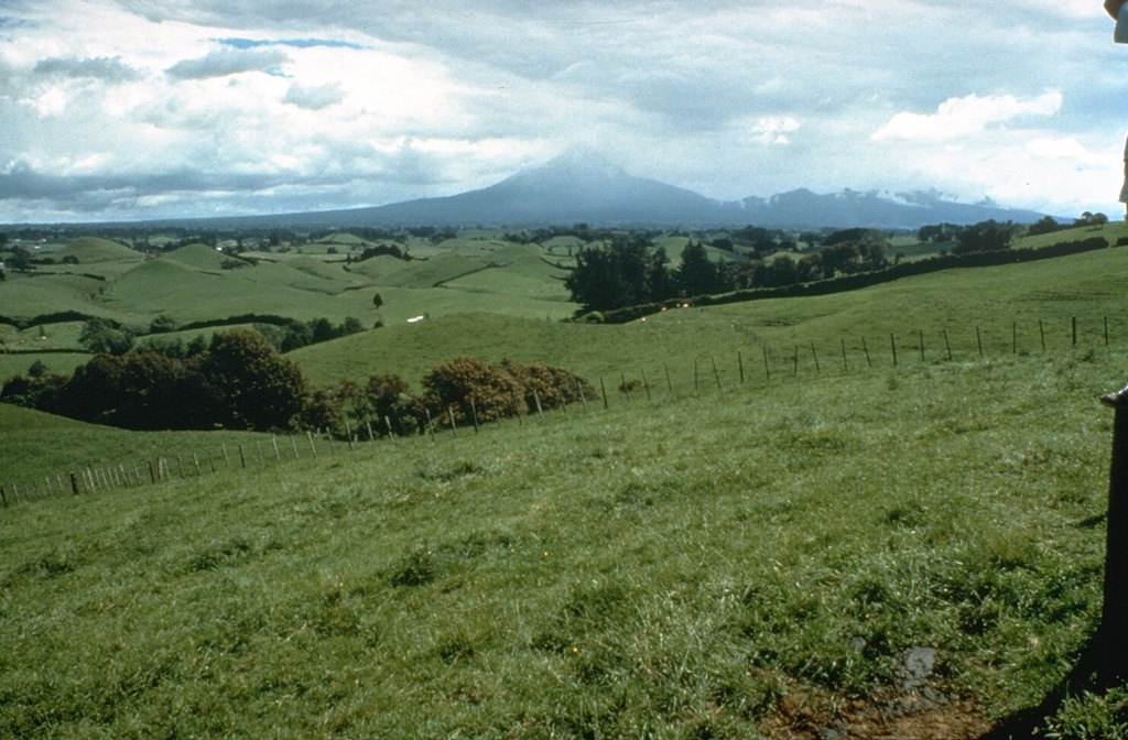 The pasture-covered, hilly terrain in the foreground is part of a vast ring plain of debris avalanche and lahar deposits surrounding Mount Taranaki. Repetitive collapse of the volcano during the late Pleistocene and Holocene produced debris avalanches that reached the W coast, nearly 40 km away. Photo by Dan Miller (U.S. Geological Survey).