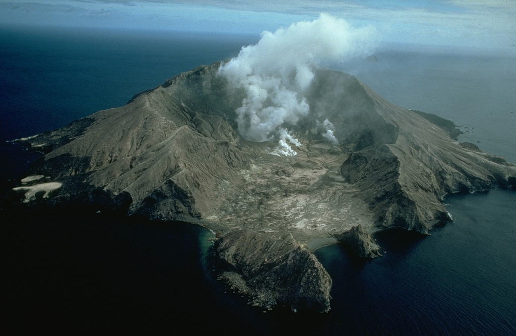 Steam rises from the crater of White Island (also called Whakaari), one of the most active volcanoes of New Zealand. The small, uninhabited 2 x 2.4-km-wide island lies 50 km NE of the North Island. Frequent small-to-moderate explosive eruptions have been recorded since 1826, and Maori legends record earlier eruptions. This view from the SE shows the two overlapping 0.4 x 1.2 km wide craters at the summit of the largely submerged volcano. Copyrighted photo by Stephen O'Meara.