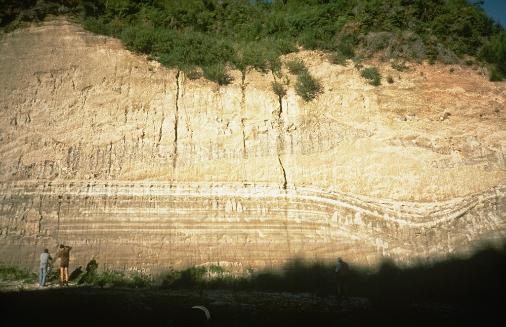 This thick outcrop exposes deposits of the 1,800-year-old Taupo eruption, one of the world's largest during the past 10,000 years. The Taupo eruption produced phreatomagmatic surge deposits, Plinian tephra deposits, and the overlying Taupo ignimbrite, seen at the upper half of this photo above the thin, light-colored layers. The eruption occurred from a vent at Horomatangi Reefs, now submerged beneath Lake Taupo. Photo by Richard Waitt, 1986 (U.S. Geological Survey).