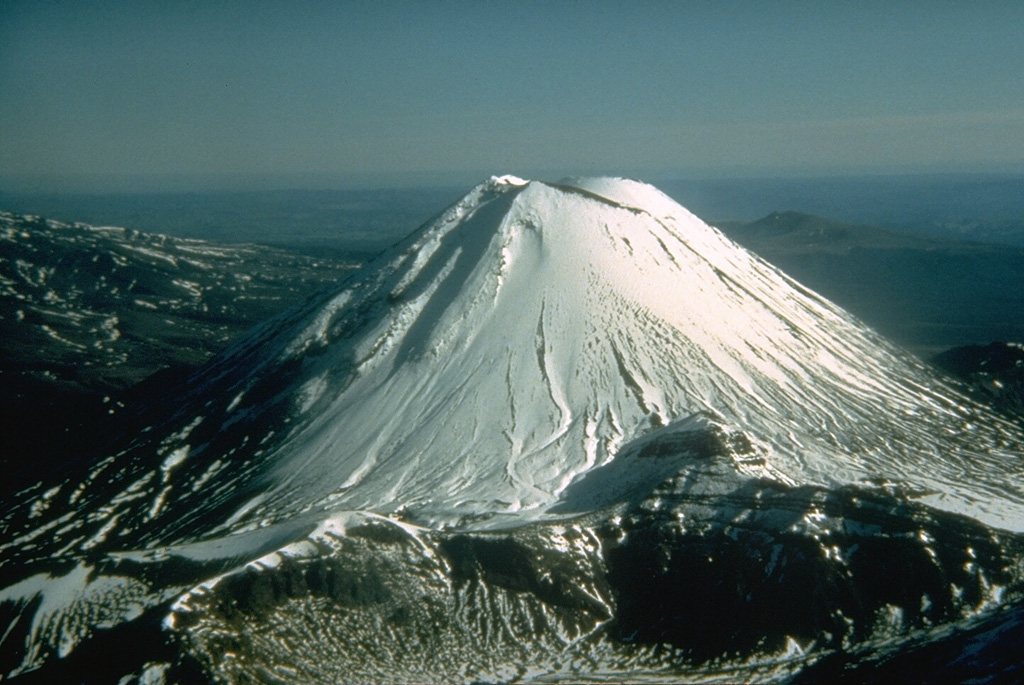 Snow-capped Ngauruhoe, seen here from the NE, rises 800 m above its surroundings and is the highest peak of the Tongariro massif. This large massif is located immediately NE of Ruapehu volcano, and is comprised of more than a dozen cones and craters. Frequent explosive eruptions have been recorded from Ngauruhoe since 1839. Photo by Don Swanson, 1984 (U.S. Geological Survey).