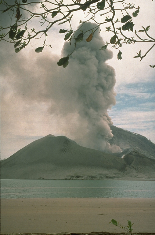 An ash plume rises above Tavurvur volcano on 3 October 1994, two weeks after the onset of a major eruption of Rabaul caldera. Tavurvur, one of two volcanoes that were active on opposite sides of the caldera, is seen here from the west at Kaputin Point on Matupit Island. The brown area in the foreground is a raft of floating pumice from the 19 September-2 October eruption of Vulcan volcano on the W side of the caldera. Photo by Elliot Endo, 1994 (U.S. Geological Survey).