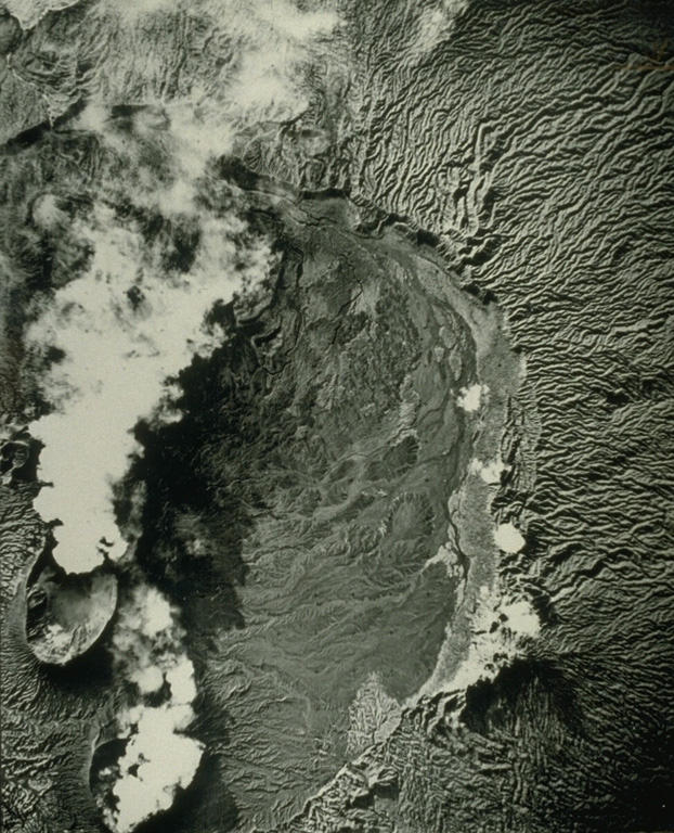This vertical aerial photo shows part of the 12-km-wide summit caldera of Ambrym. The craters emitting plumes to the lower left are Marum (top) and Benbow (bottom). The caldera formed during a major Plinian eruption that included pyroclastic flows about 1,900 years ago. Post-caldera eruptions, primarily from Marum and Benbow cones, have partially filled the caldera floor and also formed a series of cones and maars along a fissure system oriented ENE-WSW. Photo by Royal Air Force (published in Green and Short, 1971).