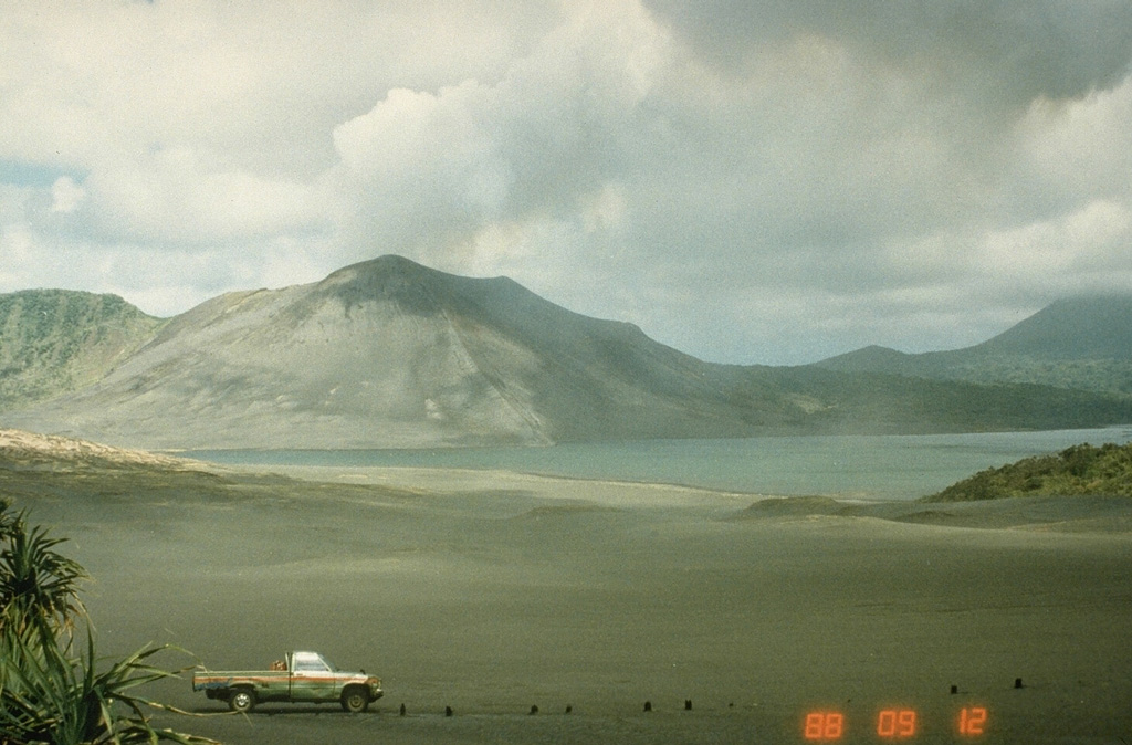 A plume rises above the summit crater of Yasur, seen here from the west across Lake Siwi in 1988. Yasur has produced near-continuous Strombolian activity since at least 1774 and this style of activity may have continued for the past 800 years. The mostly-unvegetated cone is has a 400-m-wide summit crater. Photo by Ian Nairn, 1988 (New Zeland Geological Survey).