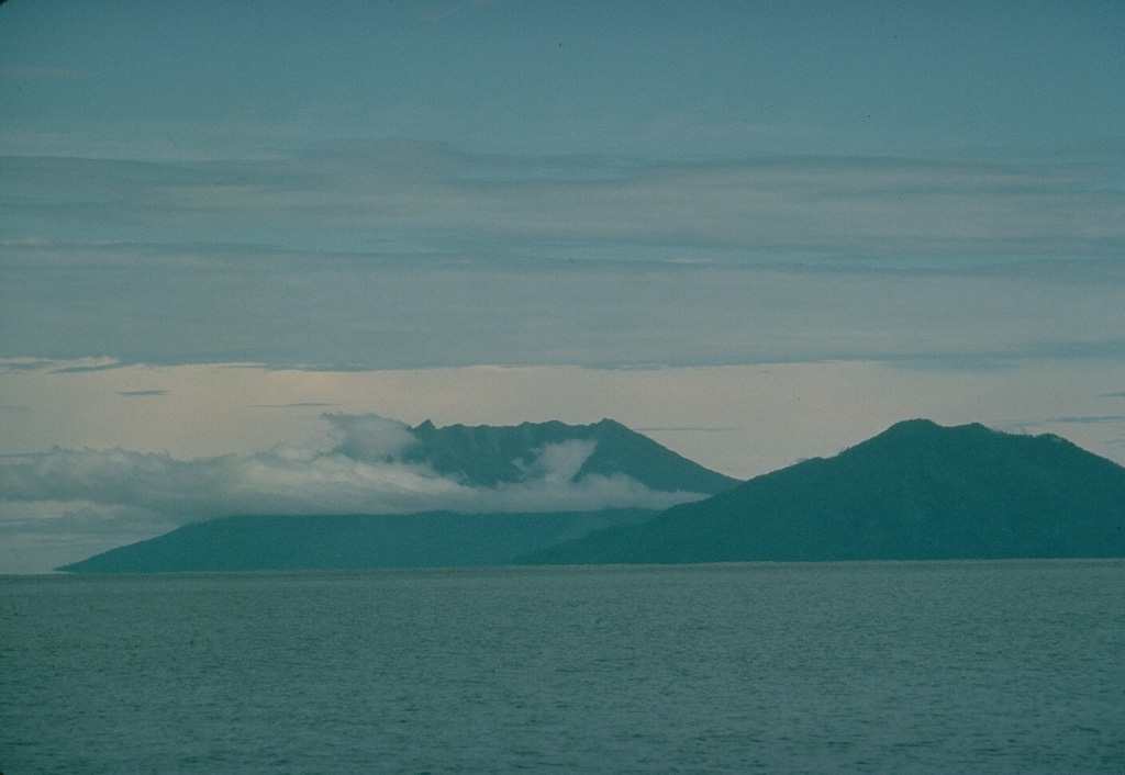 Two volcanoes of the North Maluku islands rise above the sea surface to the SW across the strait west of Halmahera Island.  On the right is the 5-km-wide island of Moti, also known as Motir.  The truncated, conical island is surrounded by coral reefs, and contains a crater on its SSW side.  There are no confirmed historical eruptions from Moti, but flat-topped Makian volcano (left) has been the source of several powerful eruptions since the 16th century that have devastated the 10-km-wide island. Copyrighted photo by Katia and Maurice Krafft, 1976.