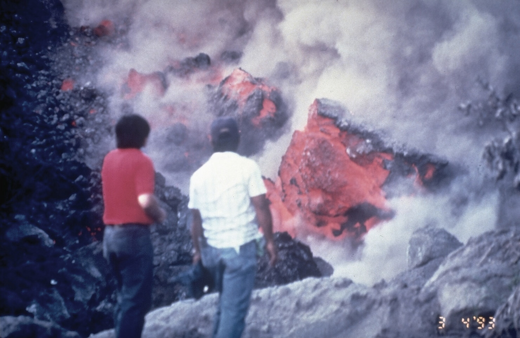 Volcanologists of the Philippines Institute of Volcanology and Seismology examine the front of a slow-moving lava flow that is advancing down the SW flank of Mayon volcano in March 1993. The incandescent interiors of lava blocks are exposed as they tumble down the sides of the flow. Photo by Philippine Institute of Volcanology and Seismology, 1993.