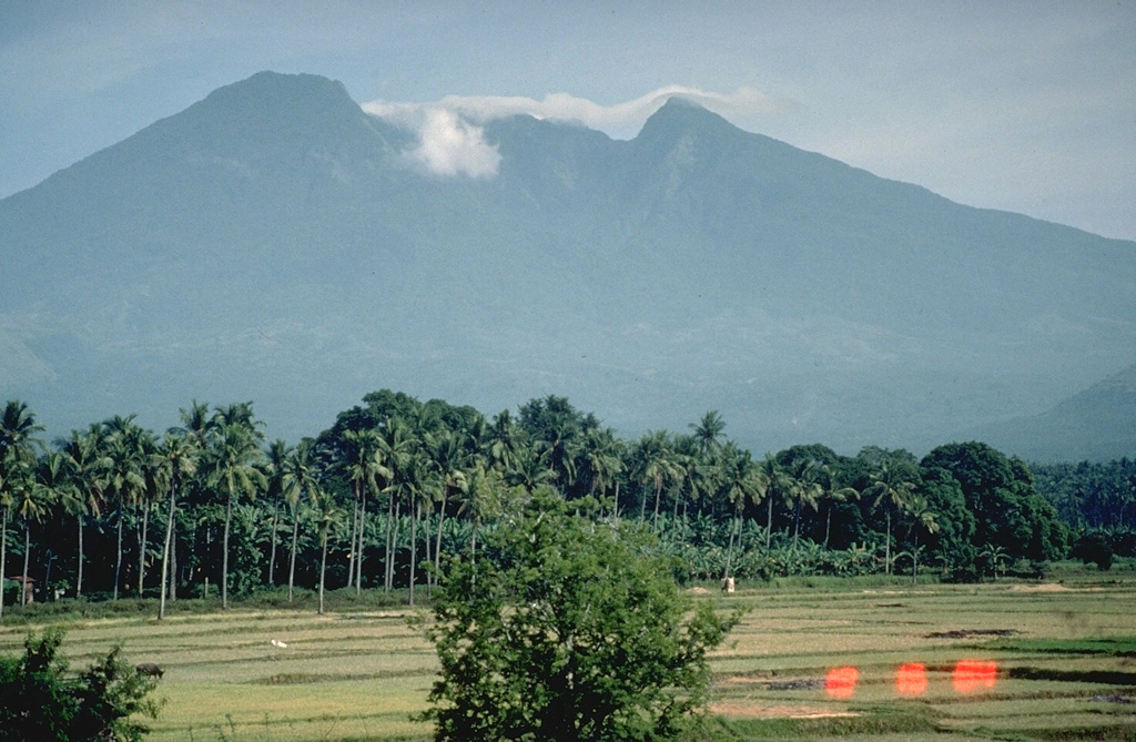 Mount Banahaw is the highest of a group of volcanoes S and E of Manila. The smaller San Cristóbal and Banáhao de Lucban have formed on the W and E flanks, respectively. This view from the SW shows a valley descending from the summit that formed or deepened during the outbreak of a crater lake in 1730. Collapse events produced two major debris avalanches, the largest of which traveled 26 km SE to the sea, where it forms a 10-km-long section of Tayabas Bay coastline. Photo by Chris Newhall, 1989 (U.S. Geological Survey).