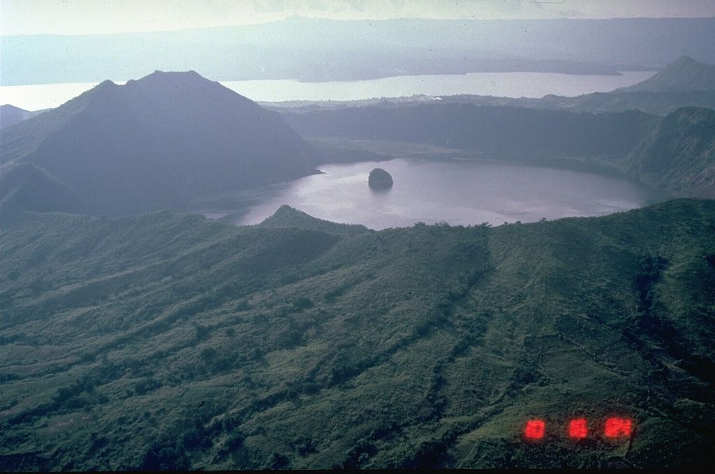 A 3-km-wide caldera is located at the center of Volcano Island, in the Philippines' southern Luzon Island. The 5-km-wide Volcano Island lies within the much larger 15 x 20 km Taal caldera, of which the western wall is seen across Lake Taal in the distance. The small island in the center of the photo is a remnant of historical eruptions on Volcano Island and is an island in a lake, on an island in a lake, on an island. Photo by Chris Newhall, 1989 (U.S. Geological Survey).