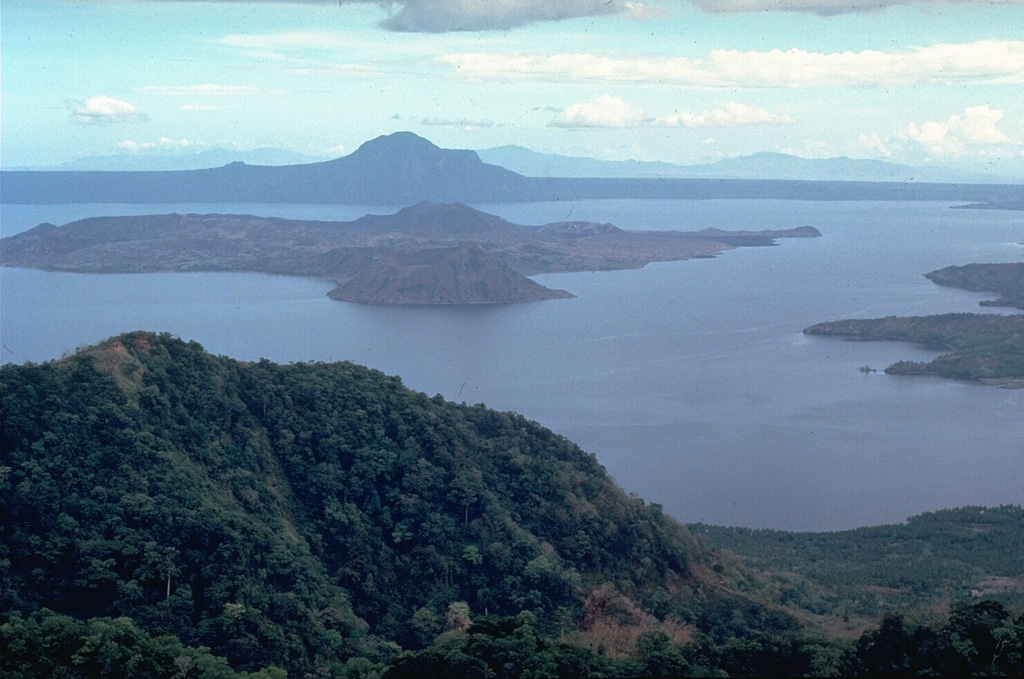 Taal caldera, seen here from its NW rim, is a 15 x 20 km caldera of Pleistocene and Holocene age. Volcano Island, in the north-central part of Lake Taal, is constructed of coalescing small tuff  and scoria cones. Powerful phreatomagmatic explosive eruptions from several locations on the 5-km-wide island have produced deadly pyroclastic surges. Photo by Chris Newhall, 1978 (U.S. Geological Survey).