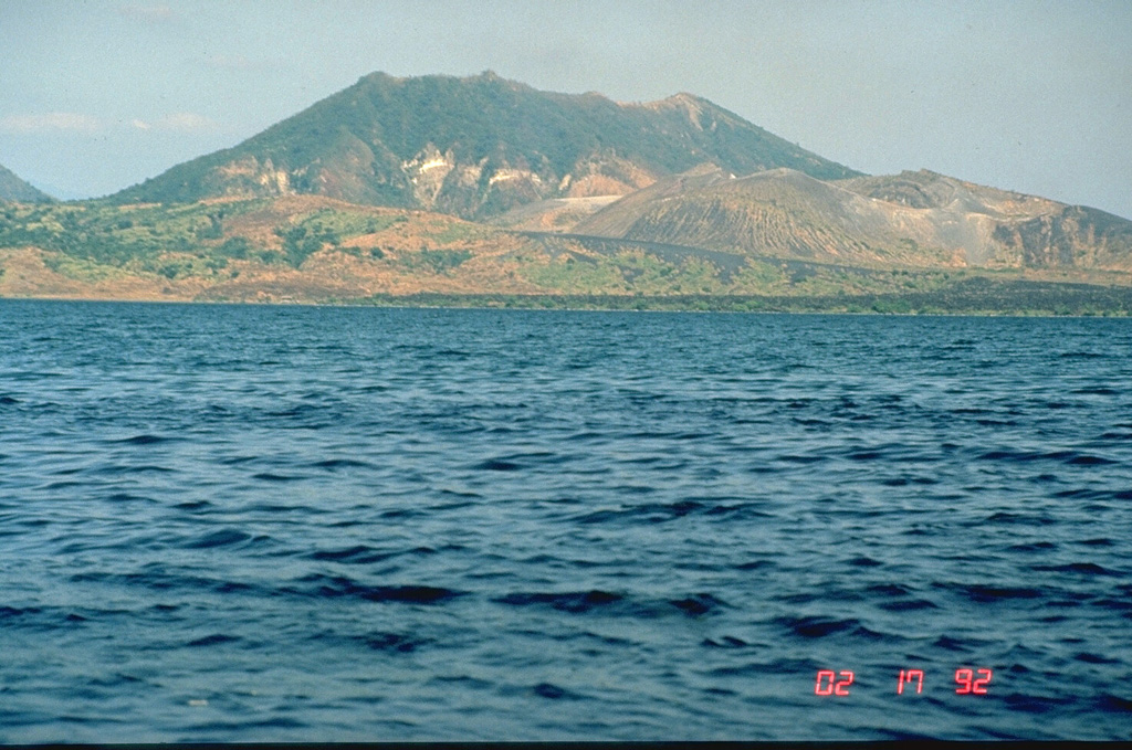 Mount Tabaro on Volcano Island at Taal is seen here from the west in 1992. The sloping ridge extending across the photo from the lower right shoreline is the rim of the elongate 1965 vent system. The dark lava flow along the coastline was erupted in 1968 from a scoria cone that formed in the 1965 vent. This and other overlapping scoria cones and craters at the right-center formed during 1966 to 1977 eruptions. Photo by Chris Newhall (U.S. Geological Survey).