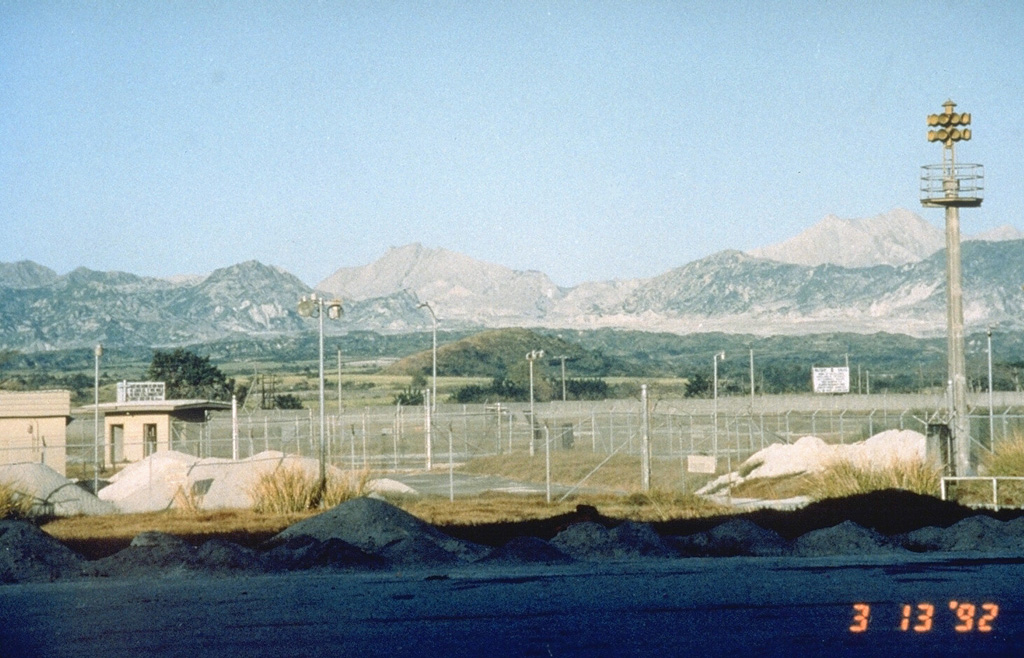 The summit of Pinatubo is seen from the E at Clark Air Base in 1992. The  unvegetated peak near the center is the southern rim of the new caldera and summit. The northern caldera rim lies about 2/3 of the distance between the summit and the unvegetated peak to the right, which is the relict caldera rim of ancestral Pinatubo volcano. Photo by Rick Hoblitt, 1992 (U.S. Geological Survey).
