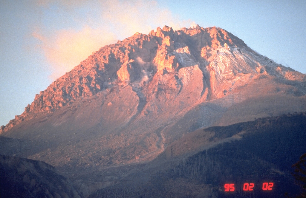 The 1990-95 eruption of Unzen volcano, in Kyushu, southern Japan, produced a lava dome at the summit. The rising sun colors the dome, seen here from the NE on 2 February 1995, near the end of the eruption. By this time the dome had grown to about 200 m above the pre-eruption surface. Periodic collapse of the growing lava dome had produced pyroclastic flows that devastated areas on the SE and NE flanks, resulting in the evacuation of thousands. Photo by Tom Pierson, 1995 (U.S. Geological Survey).