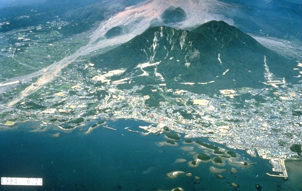 The forested islands in Shimabara harbor in the foreground were created by a massive debris avalanche in 1792 from Mayuyama, the left-most of the two forested lava domes behind the city. The high-velocity avalanche traveled 6.5 km from Mayuama and swept several kilometers out to sea. Impact of the debris into the ocean produced a devastating tsunami that swept 77 km of the shore of Shimabara Peninsula and caused nearly 15,000 fatalities. The light-colored area behind Mayuyama are block-and-ash flow deposits from the 1990-95 eruption. Photo courtesy Takashi Yamada, 1994 (Public Works Research Institute, Ministry of Construction).