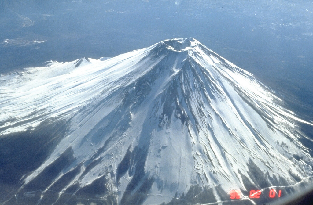 Fuji contains a 700-m-wide crater at the summit of the modern cone that is constructed over a group of overlapping volcanoes. The diagonal line to the lower right is a road that extends to the timberline on the N flank.  Photo by Tom Pierson, 1995 (U.S. Geological Survey).
