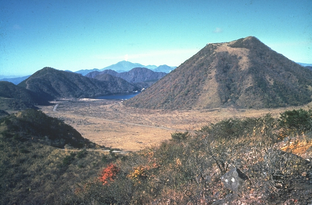 Harunasan has a small summit caldera containing Haruna-Fuji cone (right). Viscous lava flows and lava domes have formed within and around the caldera. Its western side is currently filled by Lake Haruna, which is visible to the left of the cone. The Futatsudake lava dome, outside the caldera to the E, was the source of two large explosive eruptions during the 6th century CE. This view from the NE also shows a plume emanating from Asamayama on the distant horizon above Lake Haruna. Photo by Ichio Moriya (Kanazawa University).