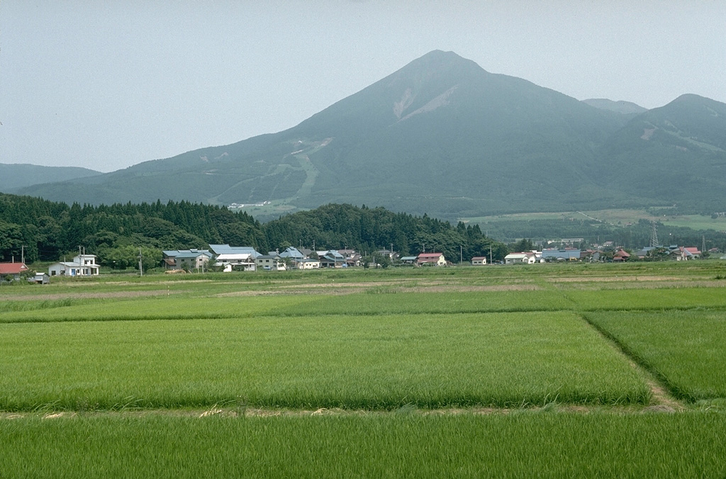 Akahaniyama to the right is one of several cones that form Bandaisan, seen here above rice fields N of Lake Inawashiro. The forested ridge in the left foreground is part of an earlier Pleistocene debris avalanche deposit. Photo by Lee Siebert, 1988 (Smithsonian Institution).