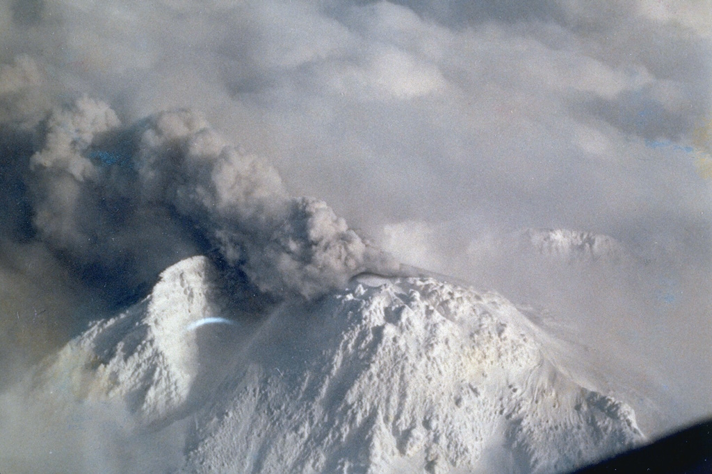 An ash plume rises from the Shinzan lava dome at the summit of Chokaisan on 1 March 1974 after a repose of 140 years. Phreatic eruptions occurred in March and April that produced small lahars. The eruptions took place from an E-W-trending series of vents extending from the eastern caldera wall across the 1801 Shinzan lava dome and the Kojinyama cone. This view from the NW shows the eastern caldera wall behind the dome. Photo courtesy of Japan Meteorological Agency, 1974.