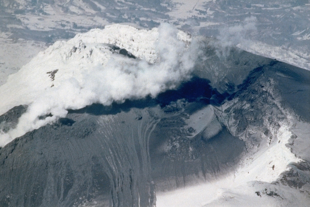 A plume rises from a vent on Chokaisan on 24 April 1974 near the end of an eruption that began on 1 March. Ash deposits cover the slopes of the summit and lahar deposits descend the flanks to the lower left in this view from the SW. Shinzan lava dome appears above the plume to the left, with the eastern caldera wall in the background. The 1974 eruption, the first from Chokaisan in 140 years, ended on 30 April. Photo courtesy of Japan Meteorological Agency, 1974.