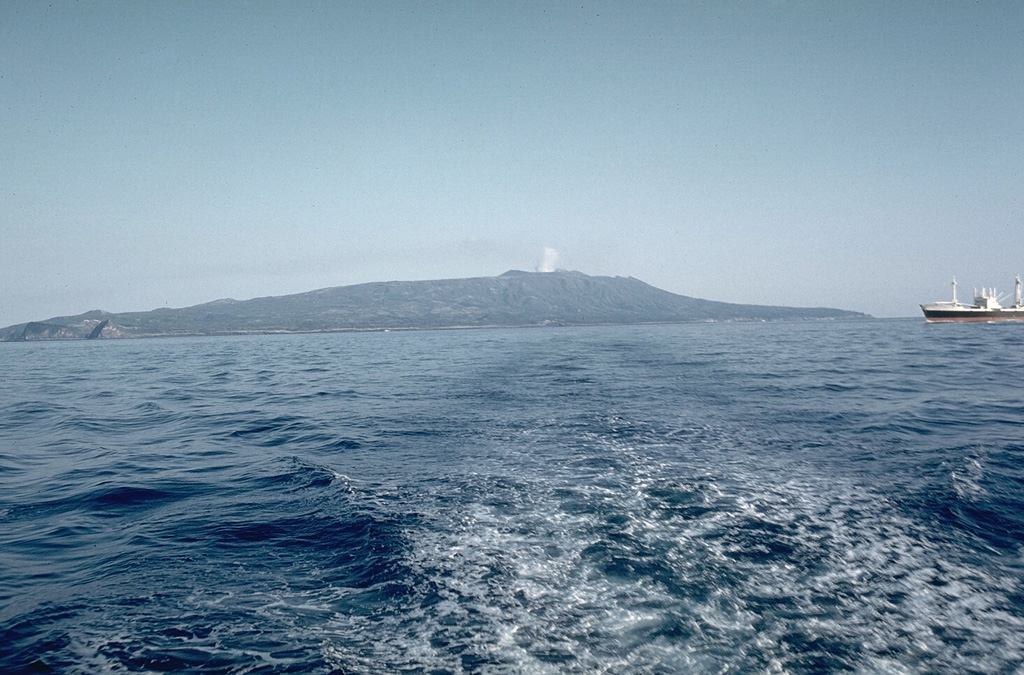 Oshima is the northernmost of the Izu Islands, seen here from the NW in Sagami Bay. The broad, low-relief volcano forms an 11 x 13 km island constructed over the remnants of three older edifices. It contains a 4-km-wide caldera containing the Miharayama cone, seen here producing a small plume in 1961, which has produced numerous recorded eruptions. Photo by Richard Fiske, 1961 (Smithsonian Institution).