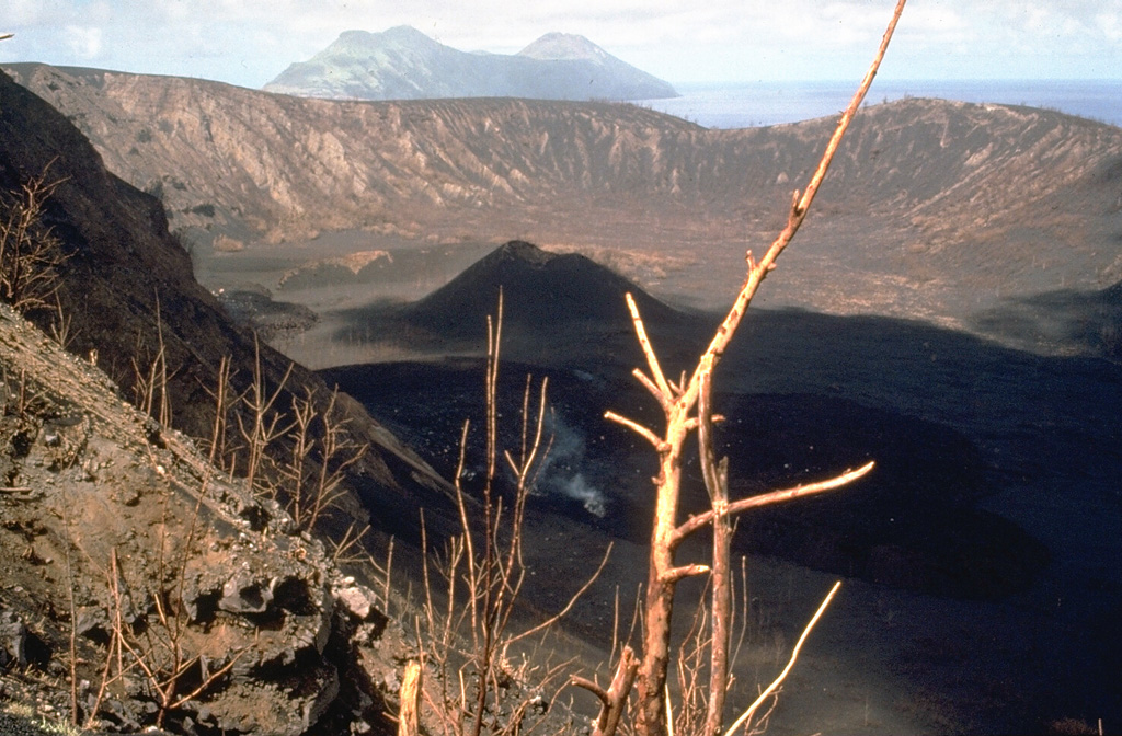 Two maars on the western flank of North Pagan volcano. Pyroclastic surge deposits from the latest eruption of the 1.5-km-wide eastern maar, seen here from the NE with South Pagan volcano in the distance, were radiocarbon dated to about 150 years old. This 24 May 1981 photo shows a lava flow (producing a gas plume) that originated from the summit crater during an eruption that began on 15 May. Photo by Norm Banks, 1981 (U.S. Geological Survey).