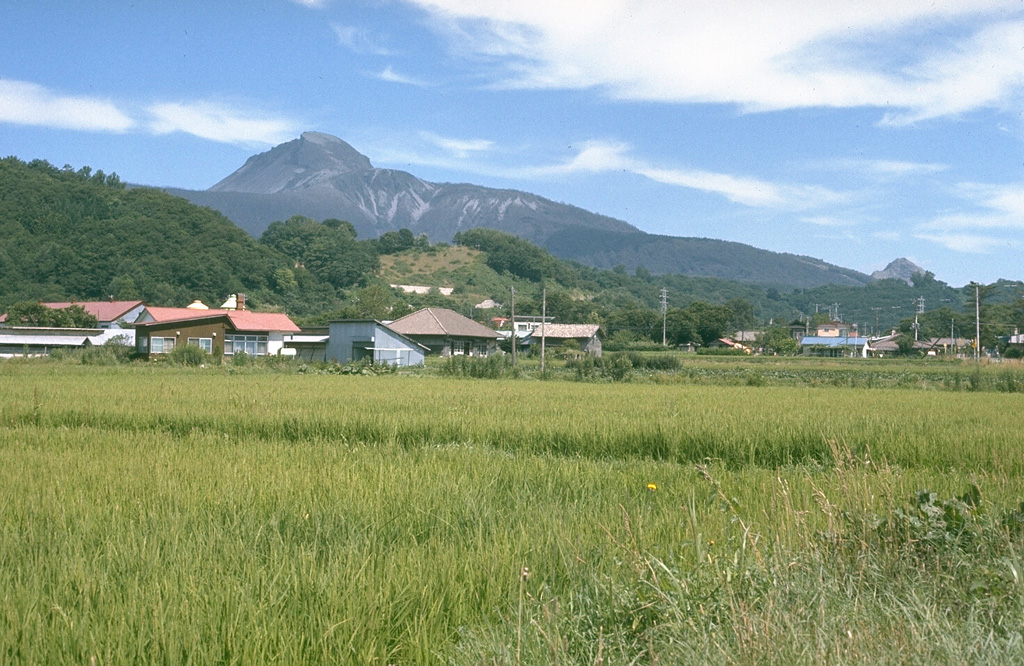 O-Usu lava dome (left center), the largest of several lava domes constructed in the summit crater of Usu volcano, formed during a major eruption in 1853. The eruption began on 22 April. The Kaei (Tateiwa) pyroclastic flow may have erupted on 27 April. Major explosive activity ended in early May and was followed by the growth of the dome. Two cryptodomes on the SE flank are thought to have formed at the same time as O-Usu. It is seen here from the S, with the 1944-45 Showa-Shinzan dome forming the small peak to the right. Photo by Lee Siebert, 1977 (Smithsonian Institution).