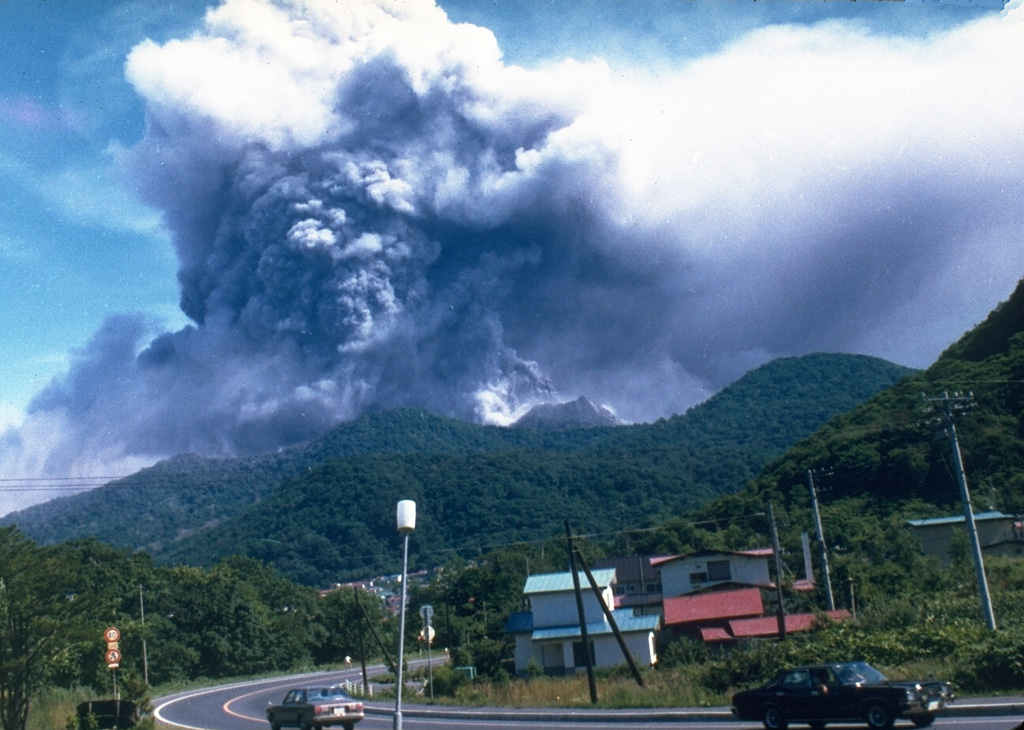 An ash plume rises above Usu on the afternoon of 7 August 1977, the first day of an eruption that lasted until 1982. Nine major explosive eruptions during 7-14 August 1977 were followed by slow growth of the Usu-Shinzan cryptodome. A crypotodome is a lava dome that uplifts the ground without breaking through to the surface. Photo by T. Kobayashi, 1977 (courtesy Tokiko Tiba).