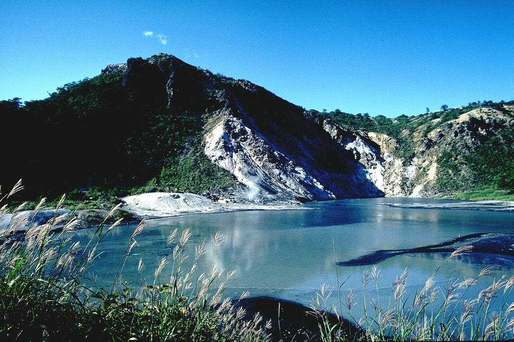 Hiyoriyama lava dome (left) was extruded during late stages of the eruption that produced the Oyunuma crater in the foreground. The dome is mantled by a thin layer of older sediments and breccias that were baked during uplift of the dome. The crater is 300-400 m wide and filled with hot water. Photo by Tom Simkin, 1981 (Smithsonian Institution).