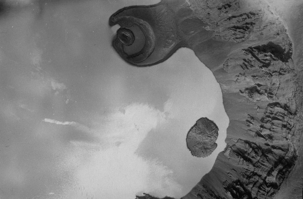 Zavaritzki volcano contains three nested calderas that are 10, 8, and 3 km in diameter. The walls of the youngest caldera are seen here in an aerial view taken before a 1957 eruption that formed a new lava dome and decreased the size of the caldera lake. A scoria cone (top center in this view with N to the right) forms a peninsula on the N side of the caldera. The small lava dome in the center of the crater and the small lava dome island to the lower right were emplaced sometime between 1916 and 1931. Photo courtesy of G.S. Gorshkov, Institute of Volcanology, Petropavlovsk (published in Green and Short, 1971).