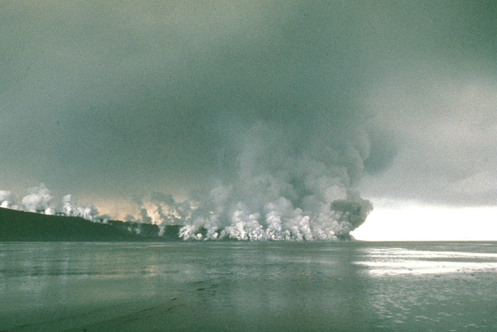 Gas-and-steam plumes rise above a lava flow advancing into the Sea of Okhotsk on the NW flank of Alaid in 1972. The flow erupted from NW-flank fissures and traveled 1 km and, creating a new 1 km2 peninsula. The eruption began with explosive activity from a 2-km-long fissure on 18 June 1972 and transitioned to lava flow extrusion beginning 21 June. Photo by Yuri Doubik, 1972 (Institute of Volcanology, Petropavlovsk).