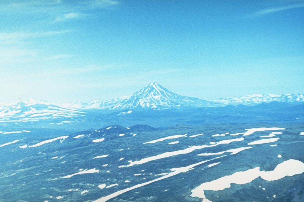 Mutnovsky (center) one of the most active volcanoes of southern Kamchatka and is formed of four coalescing edifices, seen here from the west. The complex has multiple summit craters and historical eruptions have been explosive, with lava flows produced during 1904.  Photo by Andrei Tsvetkov.