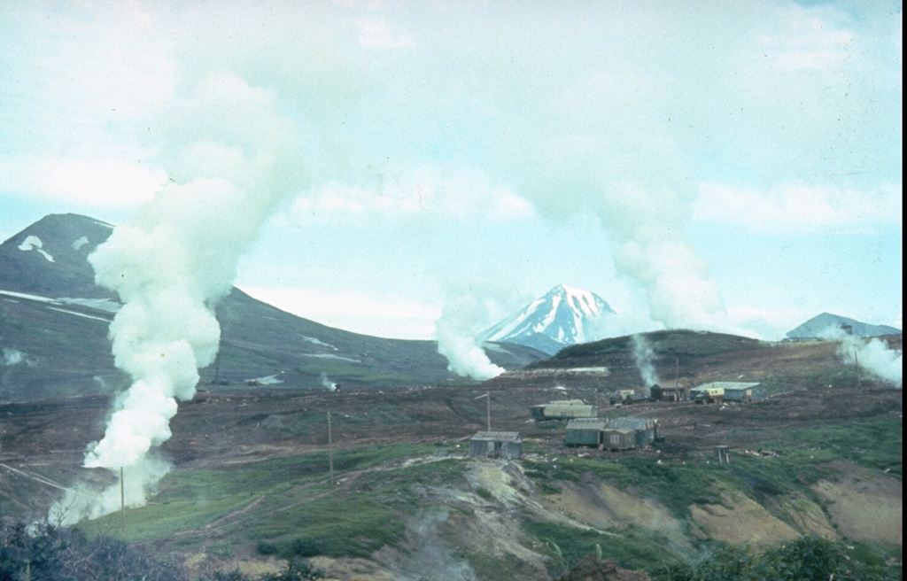 Plumes rise from geothermal prospects drilled during the late 1970's on the NE flank of Mutnovsky in this 1986 photo. The wells yielded a steam-gas mixture from depths of 60-1,200 m. The steep-sided Vilyuchik volcano appears in the background to the NE. Photo by Kamchatka Volcanic Eruptions Response Team, 1986 (courtesy of Dan Miller, U.S. Geological Survey).