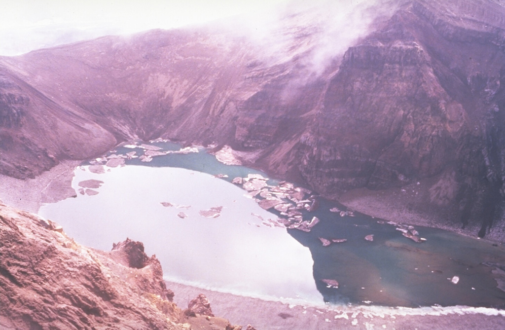 The lake in this photo is within the central of three large craters across the summit of the Gorely. Stratified deposits are exposed in the walls of the crater, which drains to the SW (lower right) through a small valley. Small icebergs float on the surface in this July 1992 view. Photo by Phil Austin, University of Southern Florida, 1992 (courtesy of Pavel Kepezhinskas).