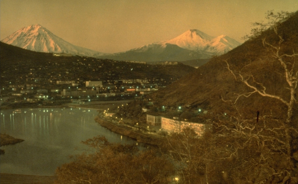 The two historically active volcanoes Koryaksky (left) and Avachinsky (right) volcanoes at dusk beyond the city of Petropavlovsk and Avachinsky bay.  Photo by Kamchatka Volcanic Eruptions Response Team (courtesy of Dan Miller, U.S. Geological Survey).