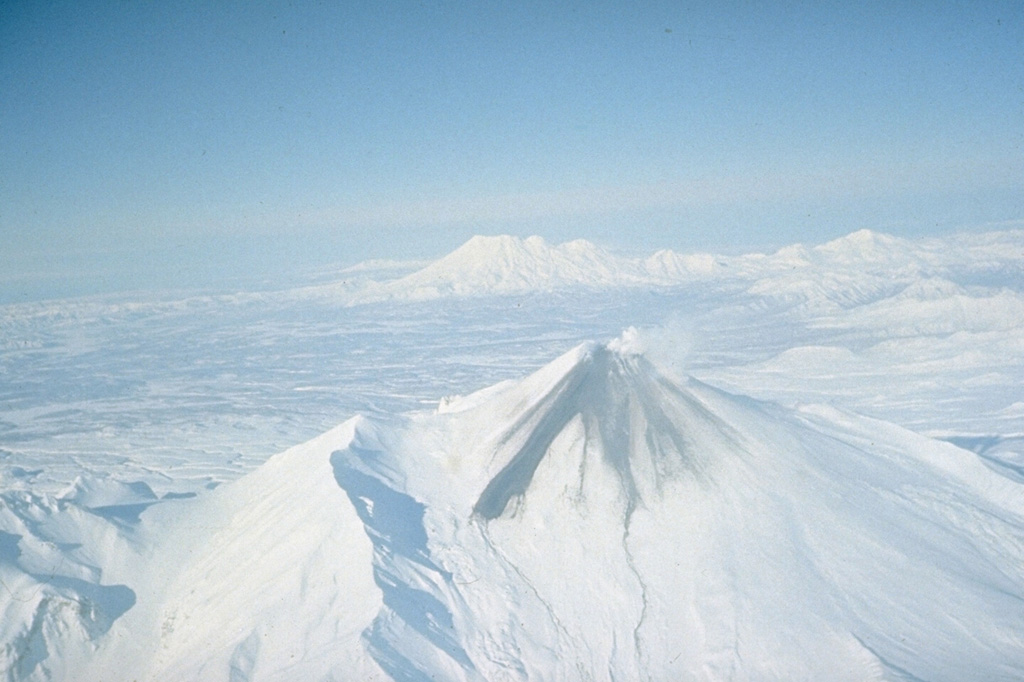 During an eruption in January 1991, lava filled the summit crater of Avachinsky and produced these dark lava flows that overtopped the S rim and traveled 1.5 km down the SSE flank. The modern cone of Avachinsky was constructed within a large horseshoe-shaped crater, with the rim visible to the right and to the left of the cone in this view. The crater formed during flank collapse during the Pleistocene. Zhupanovsky is visible to the NE. Photo by Oleg Volynets, 1991 (Institute of Volcanology, Petropavlovsk).