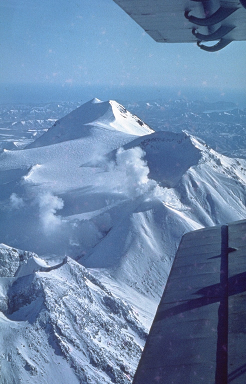 All four cones forming the WNW-trending Zhupanovsky massif are seen in this view from the west. The upper peak forms the summit of the complex. Steam plumes rise from the historically active crater in the center of the only Holocene cone; known eruptions have consisted of relatively minor explosions. Photo by Oleg Volynets (Institute of Volcanology, Petropavlovsk).