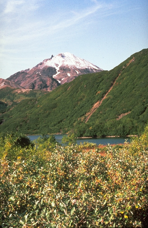 Bakening, seen here from the north, rises above a basement of metamorphic greenschists that underlie the forested slopes in the center of the photo. Lava flows overlie lava domes at the base, which is located far west of the eastern volcanic range of Kamchatka.  Photo by Pavel Kepezhinskas, 1993 (University of Southern Florida).