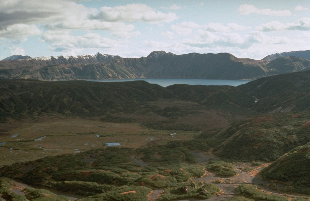 Akademia Nauk caldera in central Kamchatka, seen here from the slopes of Karymsky volcano looking SW, is one of two overlapping calderas formed during the late Pleistocene within the 15-km-wide Polovinka caldera. The snow-capped ridge to the upper left is the southern rim of Odnoboky caldera, and the northern rim is truncated by the Akademia Nauk. Karymsky Lake fills the 3 x 5 km Akademia Nauk caldera that most recently erupted in 1996. Photo by Dan Miller, 1990 (U.S. Geological Survey).