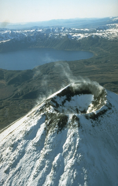 Karymsky volcano contained a 250-m-wide summit crater following the 1970-82 eruption. Karymsky Lake fills the 3 x 5 km wide Akademia Nauk caldera to the south in this early 1990's aerial photo. Both Karymsky and Akademia Nauk erupted simultaneously on 2 January 1996. The brief one-day eruption was the first historical eruption of Akademia Nauk, but long-term activity continued at Karymsky. Photo by Dan Miller (U.S. Geological Survey).