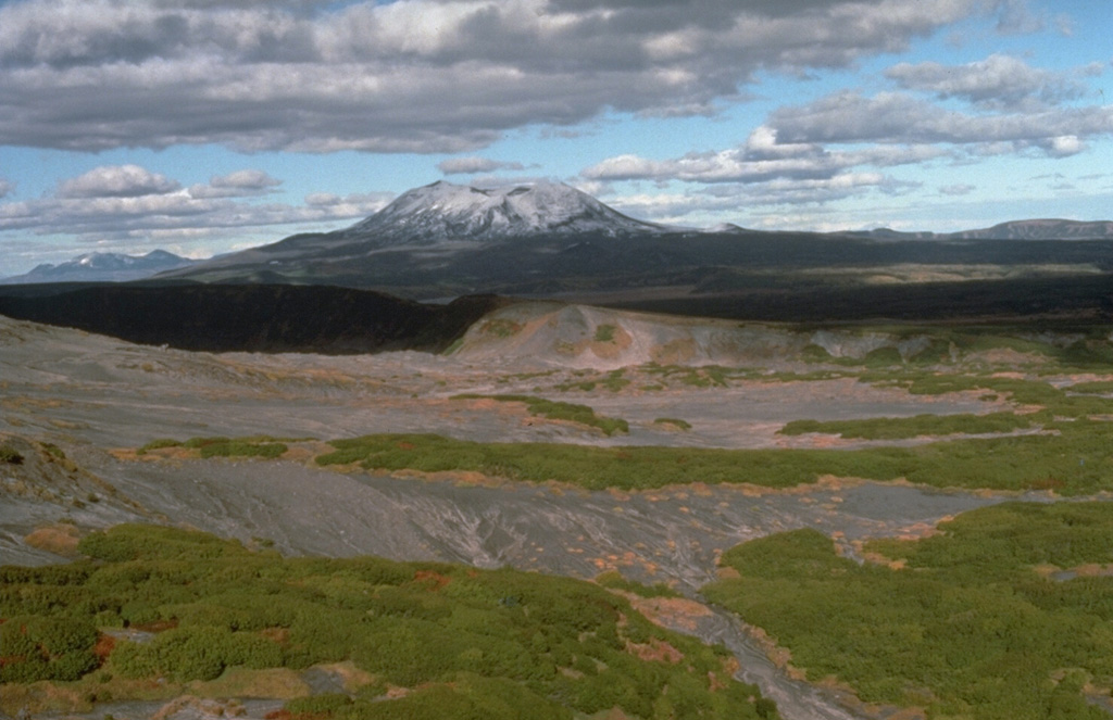 Maly Semiachik, seen here from the SW on the flanks of Karymsky, is composed of three overlapping edifices along a NW-SE line that were built within two overlapping Pleistocene calderas. The late-Pleistocene to Holocene post-caldera massif almost completely obscures the rim of the inner 7-km-wide Maly Semiachik caldera.  Photo by Dan Miller, 1990 (U.S. Geological Survey).