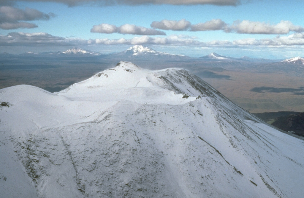 The summit of Paleo-Semyachik forms the highest point of the Maly Semyachik massif. Paleo-Semyachik, the first of three edifices constructed within two overlapping Pleistocene calderas, began forming about 20,000 years ago on the northern margin of the calderas. It produced lava flows that spread far beyond the caldera margins to the north and east before ceasing activity about 11,000 years ago. Activity then migrated to the SW, producing Meso-Semyachik volcano, whose flanks are in the foreground. Photo by Dan Miller, 1990 (U.S. Geological Survey).