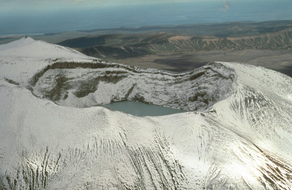 Troitsky crater, the youngest of six craters at the summit of Kamchatka's Maly Semyachik volcano, was formed during a major explosive eruption about 400 years ago. The crater, seen here from the W with the Pacific Ocean in the background, is at the summit of Ceno-Semyachik. This is the youngest of the four overlapping stratovolcanoes that comprise the Maly Semyachik massif. The crater is now filled by a hot, acidic lake and has been the source of historical eruptions. Photo by Dan Miller, 1990 (U.S. Geological Survey).