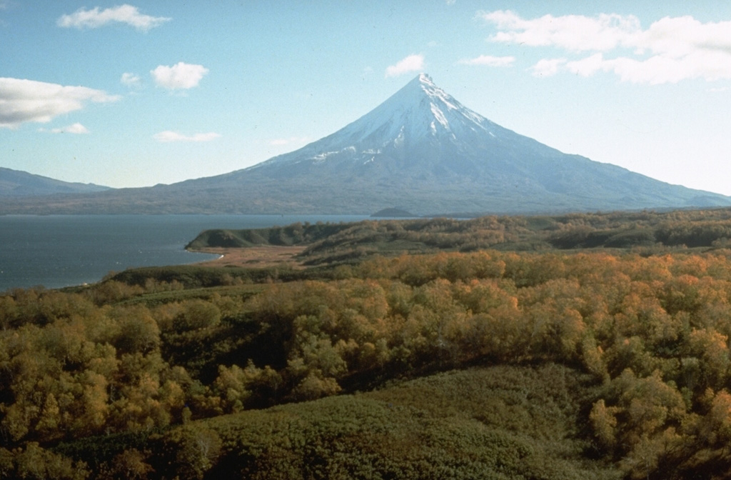 Kronotsky is seen here beyond Lake Kronotskoye, Kamchatka's largest lake. The lake formed during the late-Pleistocene to early Holocene when a series of voluminous lava flows erupted from the south flank of Kronotsky, damming the Listvenichnaya River. The SE and SW flanks contain scoria cones, and weak phreatic eruptions took place during the 20th century. Photo by Dan Miller, 1990 (U.S. Geological Survey).