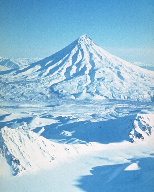 Kronotsky stratovolcano Is located between the Pacific Ocean and Lake Kronotsky, Kamchatka's largest lake. The flanks are dissected by radial valleys up to 200 m deep. Weak phreatic eruptions took place during the 20th century. Kronotsky is seen here from the SW with the caldera rim of neighboring Krasheninnikov volcano in the foreground. Photo by Yuri Doubik (Institute of Volcanology, Petropavlovsk).