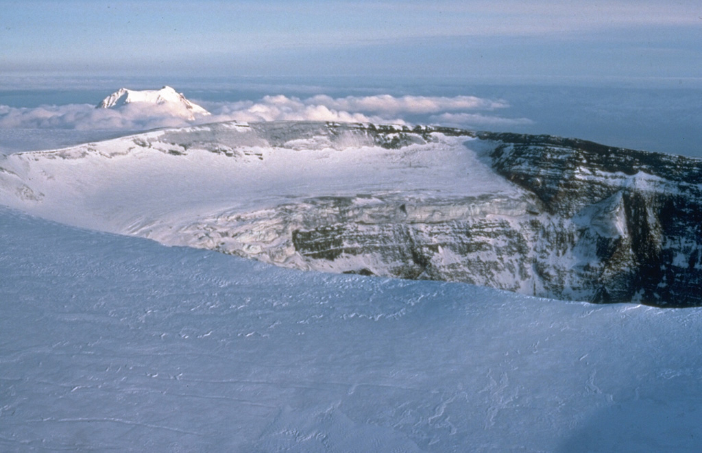 During the 1975-76 eruption a new collapse caldera formed within the Plosky Tolbachik main summit caldera. The eruption occurred along the SSW-flank rift zone 18 km away. Collapse began on 18 July following minor ash eruptions that began on 28 June. By mid-September the diameter of the caldera reached 1.2 x 1.6 km, and the depth increased from 230 to 400 m. The summit of Udina appears above the clouds to the SE. Photo by Dan Miller, 1990 (U.S. Geological Survey).