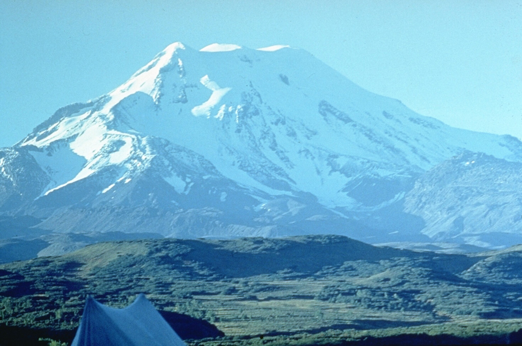 Ichinsky is the highest peak in Kamchatka's Sredinny Range, which extends along the western side of the peninsula. The summit cone of the massive stratovolcano, seen here from the south, was constructed within a 3 x 5 km-wide glacier-covered caldera. A dozen late-Pleistocene to Holocene dacitic and rhyodacitic lava domes circle the peak below the caldera rim, at elevations of 1,800-3,000 m. Fumarolic activity occurs within the caldera and on the lower N flank. Photo by Oleg Volynets, 1977 (Institute of Volcanology, Petropavlovsk).