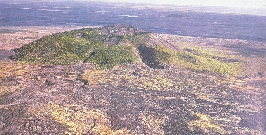 Recent lava flows surround the Laoheishan scoria cone, one of which formed during 1719-21. Four radial fissures, two of which are seen in this view from the north, were the source of most of the 1719-21 Shilong lava flows, which cover a 65 km2 area surrounding Laoheishan and the Huoshaoshan scoria cone to the NE. The dominantly pahoehoe lava flows, many of which were tube-fed, blocked local drainages and formed several small lakes at the eastern and northern margins of the lava field. Photo courtesy of Jim Whitford-Stark, Sul Ross State University, Texas (published in Feng et al., 1979).